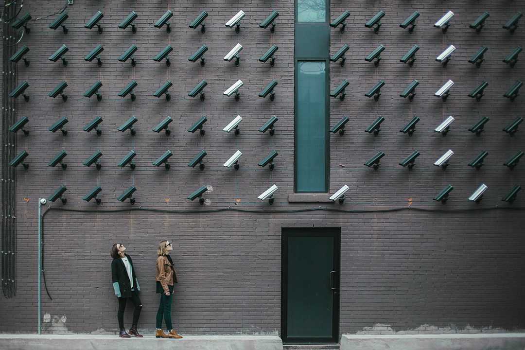 two women monitored by plenty of CCTV cameras on a single wall