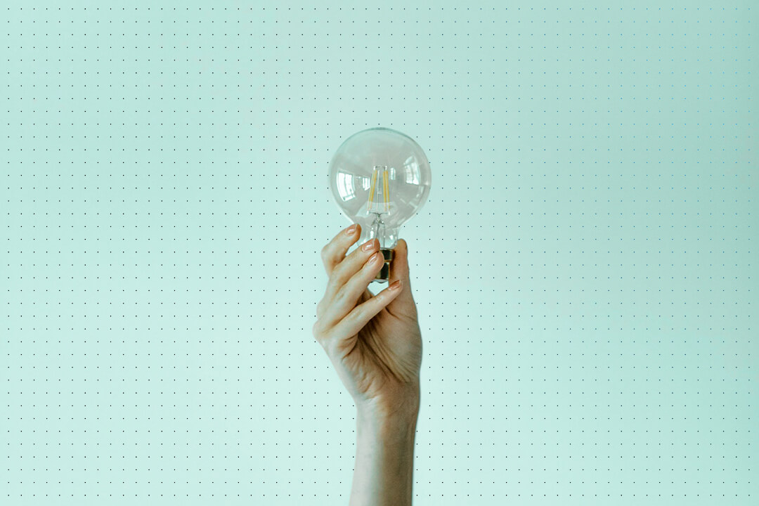 focused image of raised hand holding a light bulb