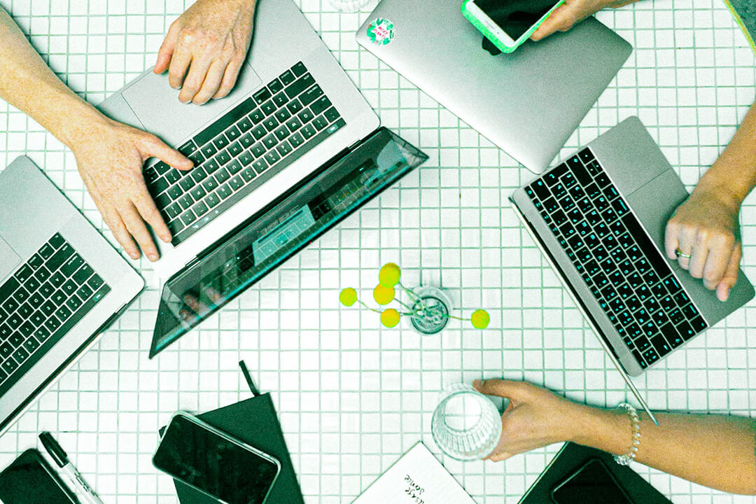 IT persons collaborating on a table with their laptops open